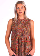 Model wears cotton sleeveless top with pleat detail across bust and hidden buttons through centre front