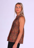 Model wears a sleeveless cotton in Indian warm floral print top that covers the hips, with tiny pleats across bust that make the lower half a relaxed fit