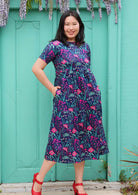 Model wearing tiered long pink and purple floral on dark blue base 100 percent cotton sundress 