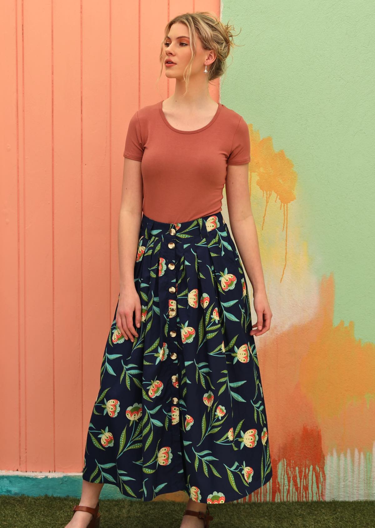 Model wears midi length cotton skirt with floral print on navy blue base