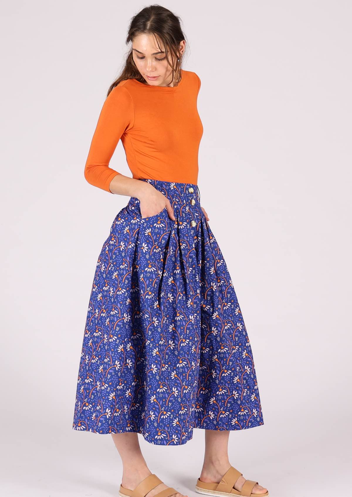 Model has her hands in the pockets of her 100% cotton, blue midi skirt. 