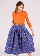 Model wears a belt loop cotton skirt with an orange top to complement the orange floral pattern. 