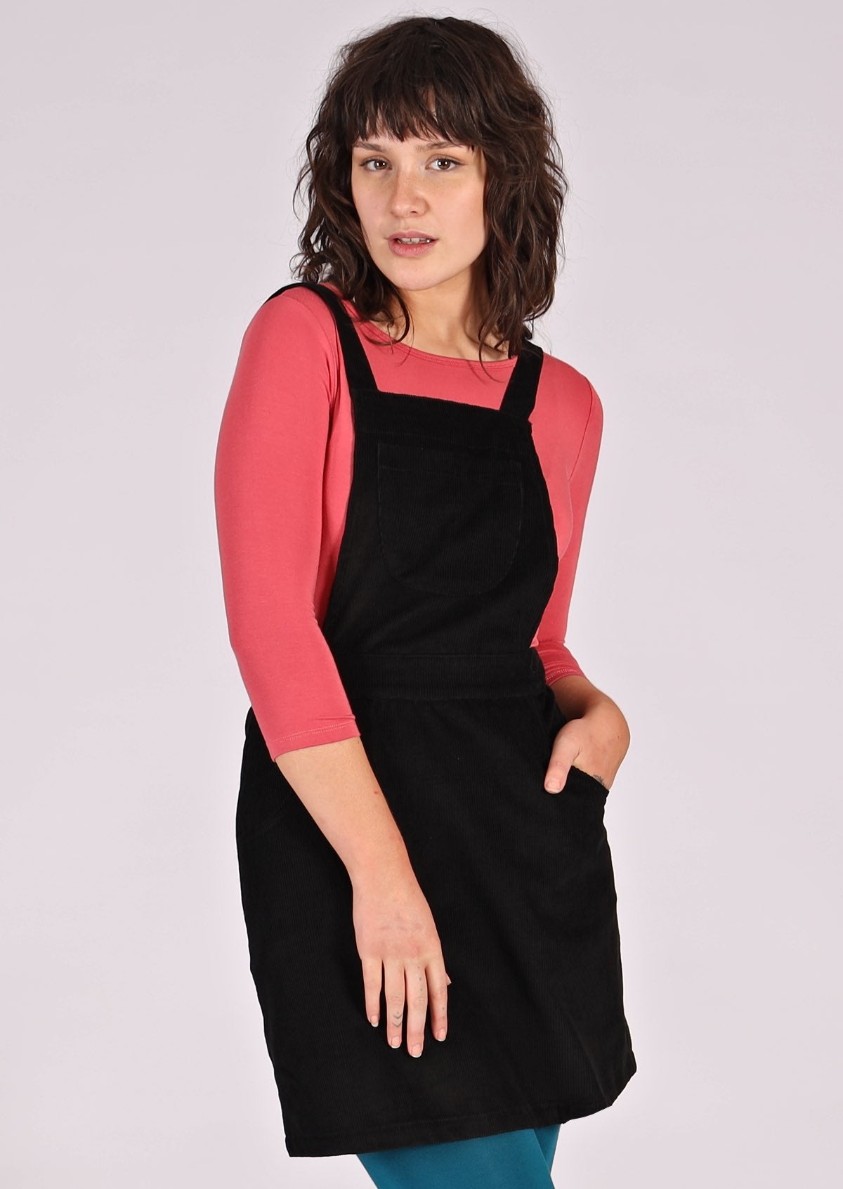 woman wearing black corduroy pinafore over pink top