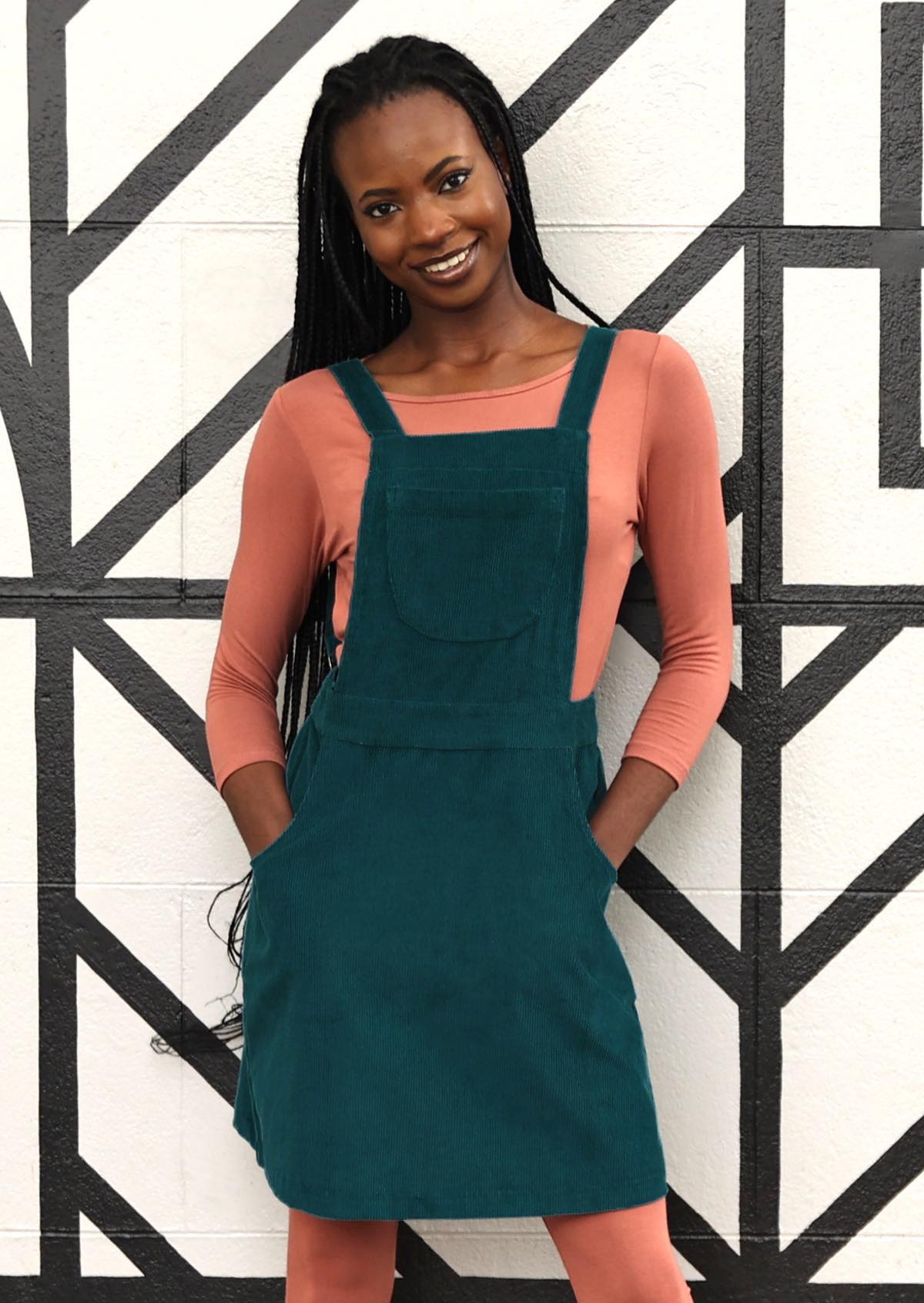 woman wearing teal corduroy pinafore over pink top