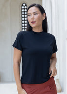 Woman wearing a black rayon crewneck t-shirt and rust pants