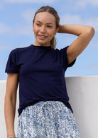 Woman wearing a navy blue t-shirt and floral skirt against a blue sky.