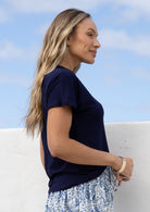 Woman wearing a navy blue stretch rayon  t-shirt and floral skirt against a blue sky.