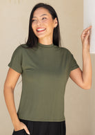 Woman wearing an olive green short-sleeve crewneck rayon top against a beige background