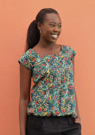 Smiling model wears a green based floral 100% cotton top. 