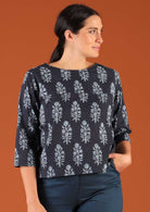 Woman with dark hair in navy blue boxy style blouse with 3/4 sleeves worn with blue cotton pants
