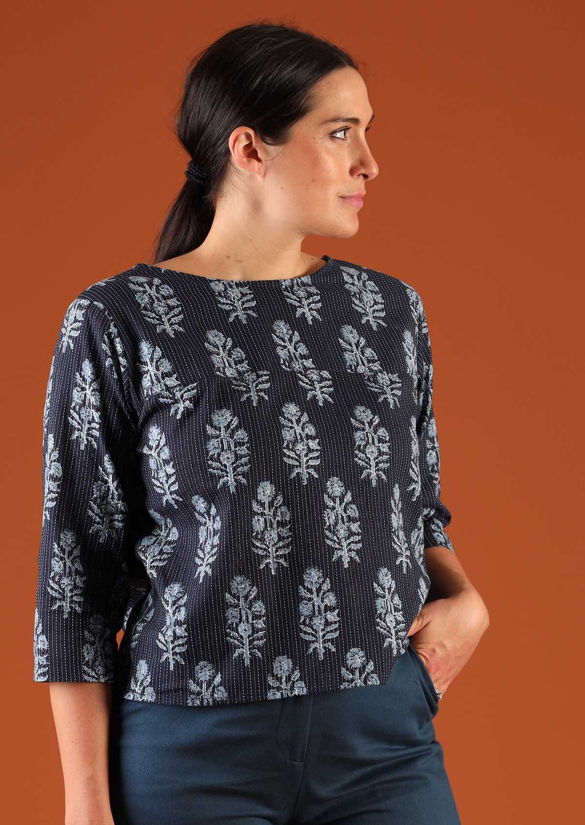Woman with dark hair in navy blue boxy style blouse with 3/4 sleeves