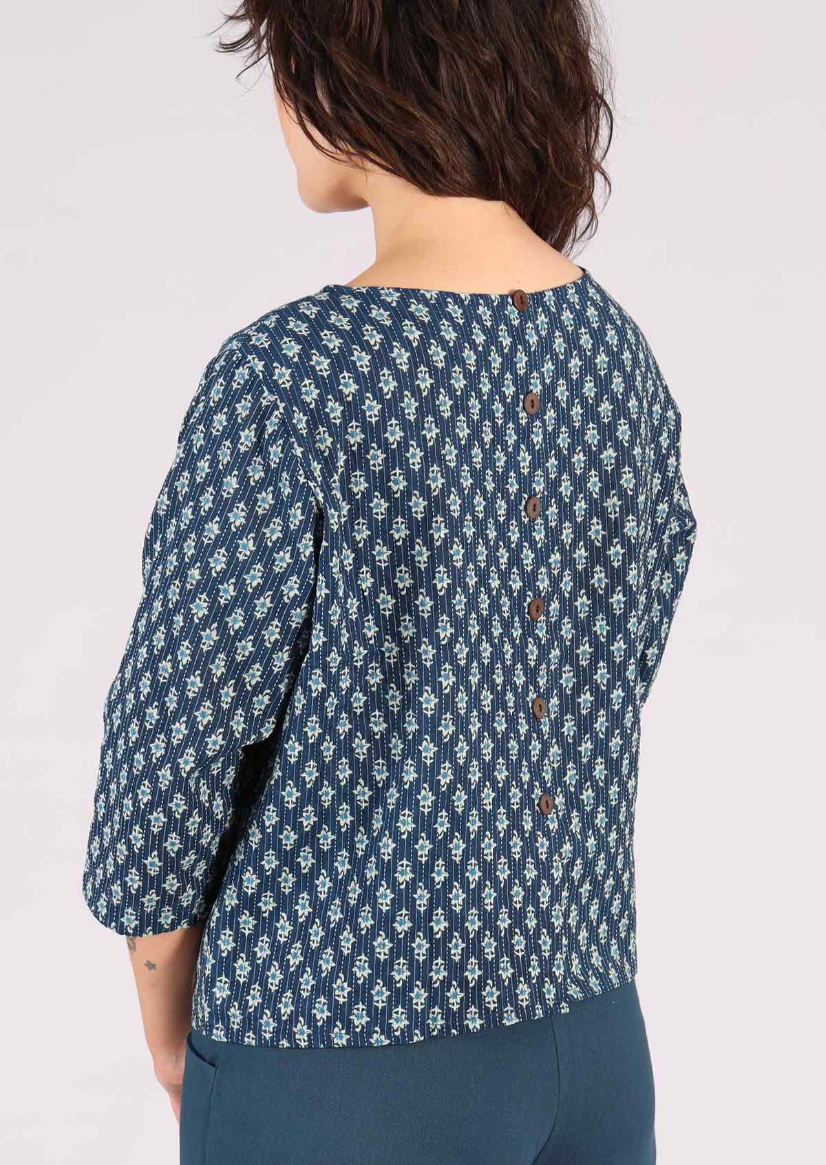 Blue cotton top features brown non-functional buttons down the back. 