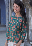 Woman stands sideways in 100% cotton loose fit top with 3/4 sleeves and round neckline