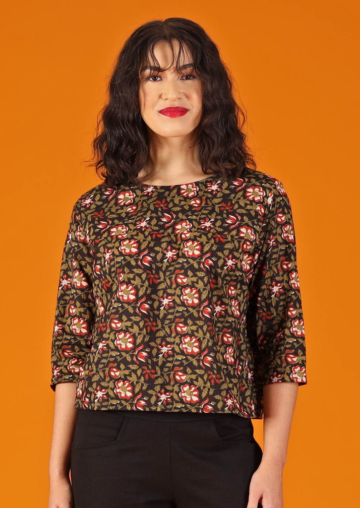 woman with dark hair and red lipstick in boxy cotton blouse, black with floral design 