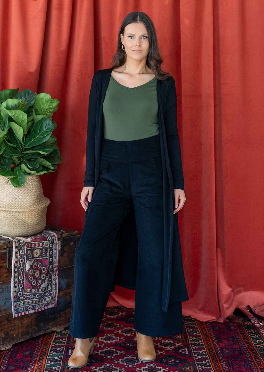 Woman wearing long black stretch jersey duster jacket over black corduroy pants 