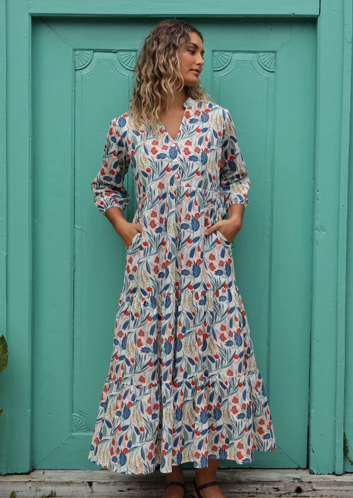 Model wears a maxi dress with pockets that is styled with sandals. 