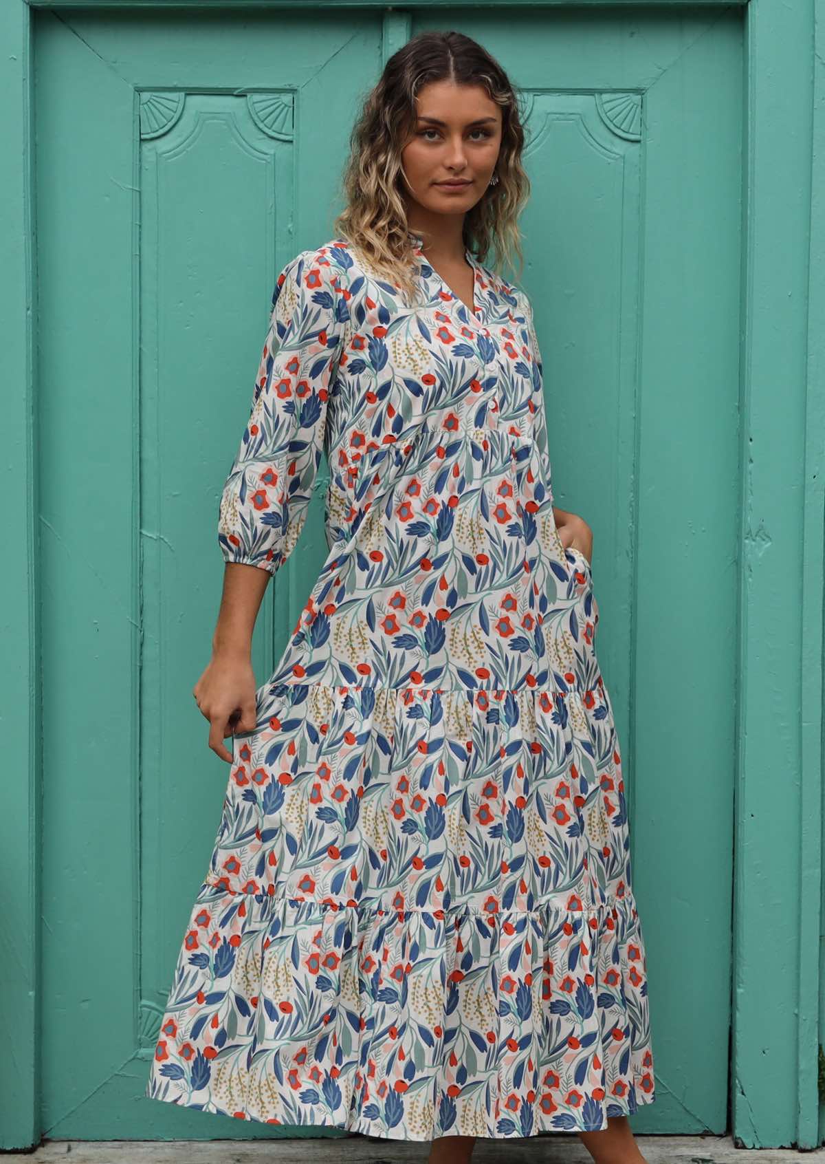 Woman wears a three tiered maxi dress with white buttons on the front. 