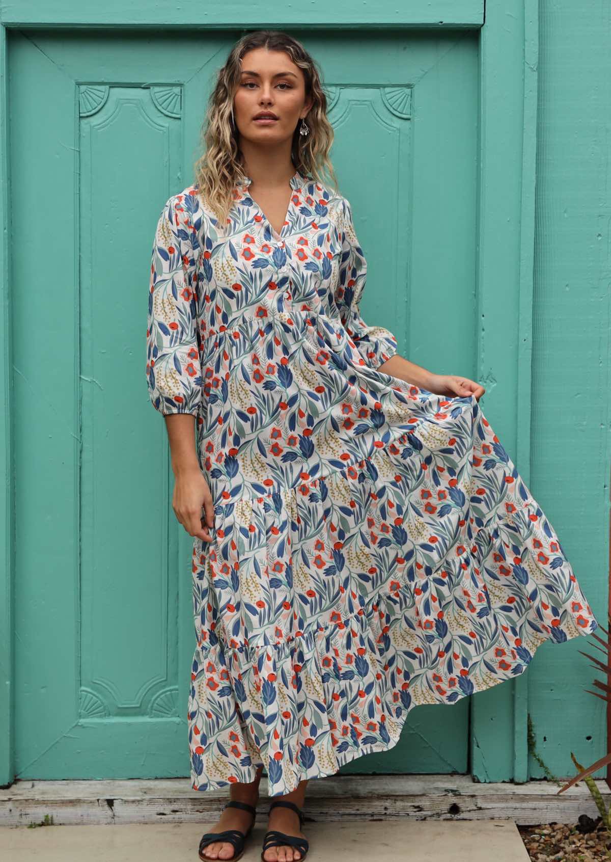 Model wears a maxi dress with 3/4 sleeves, styled with earrings. 