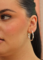 Thick silver hoop earring on woman with dark hair