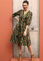 Model wears green orange and white speckled print on black base cotton wrap dress