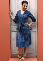 Model pairs romantic cotton dress with brown wedges. 
