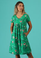 Model wears 100% cotton dress with side pockets with green base and white floral design