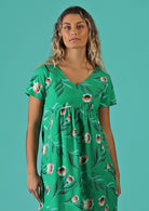 Woman wears a green dress with a floral print. 