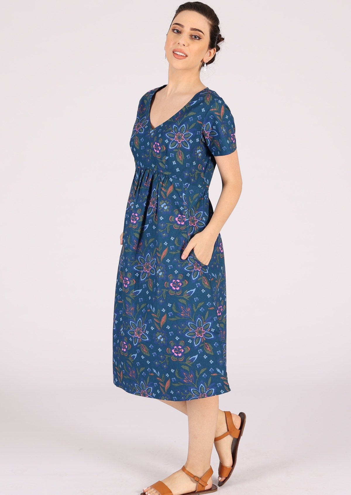 Model pairs knee length cotton dress with brown sandals and silver earrings. 