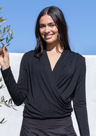 Woman wearing a black long sleeve crossover top against a blue sky background