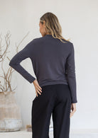 Back view of woman in dark grey stretch rayon long sleeve top paired with black pants