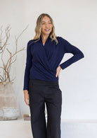 Woman wearing a navy blue cross over long sleeve top with black pants