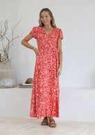 Woman wearing orange wrap around maxi dress with hand on hip 
