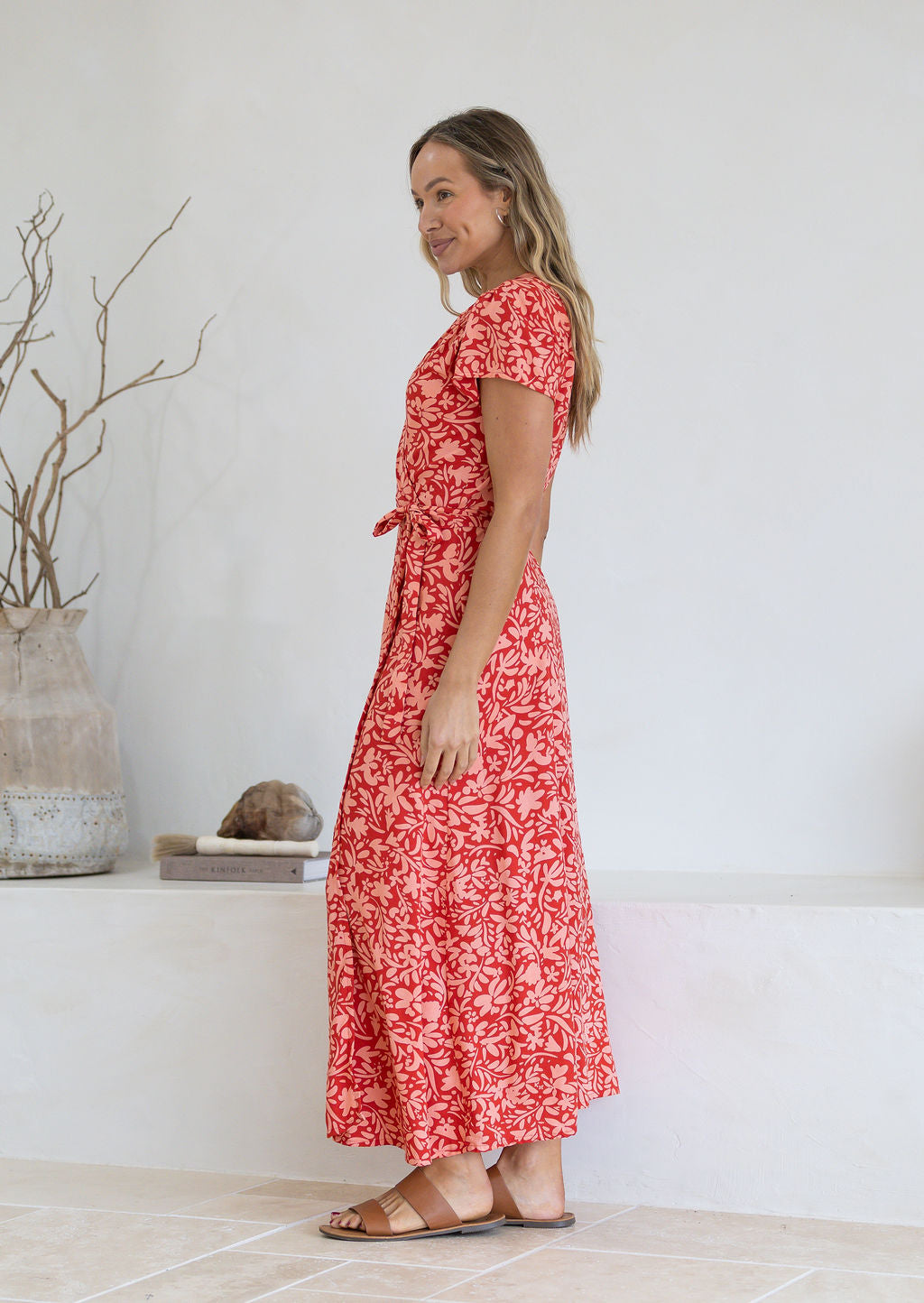 Woman wearing orange wrap around maxi dress with cap sleeves and tan sandals 