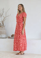 Woman wearing orange wrap around maxi dress with tan sandals 