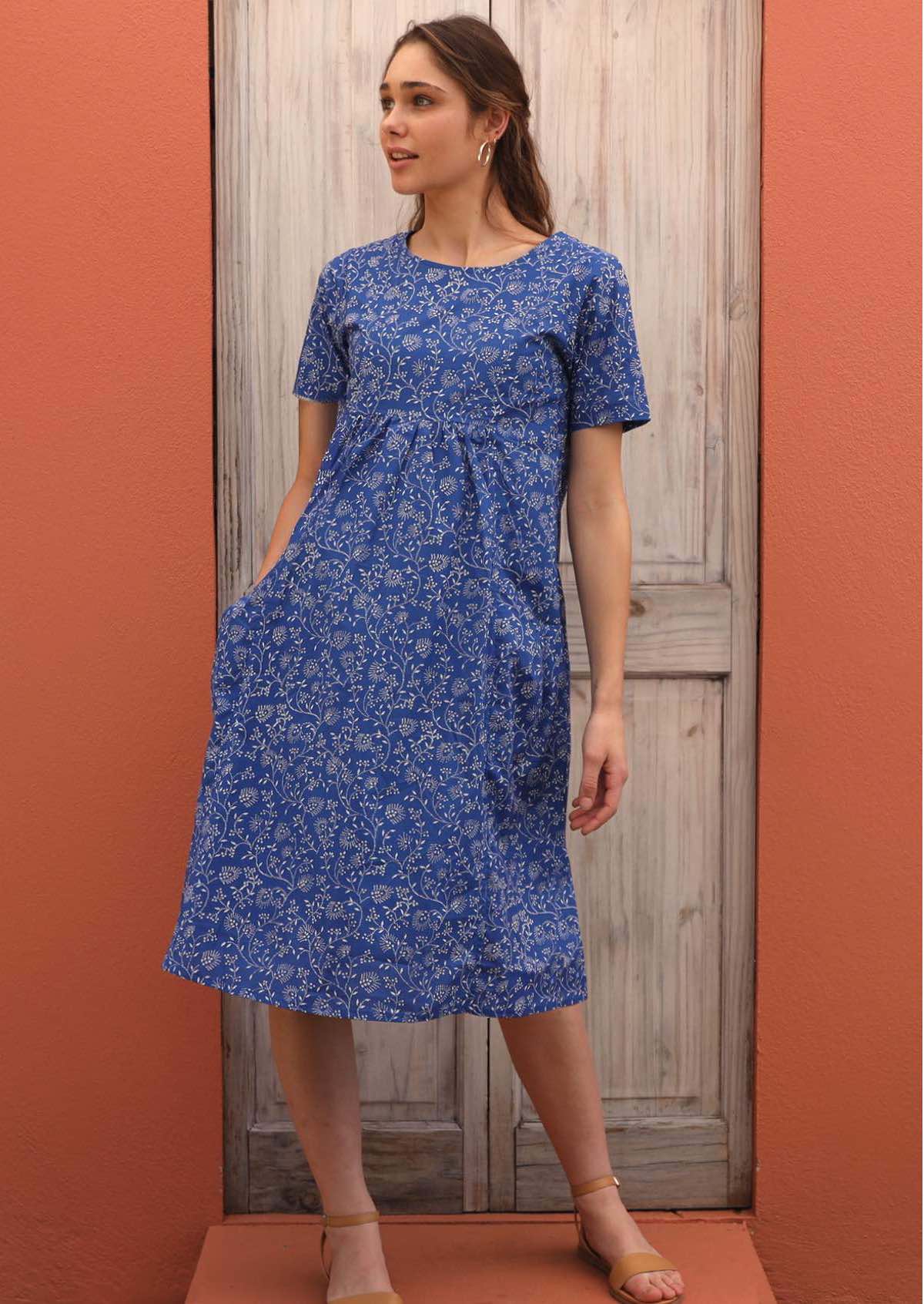 Model showcases blue base dress with a delicate white floral pattern. 
