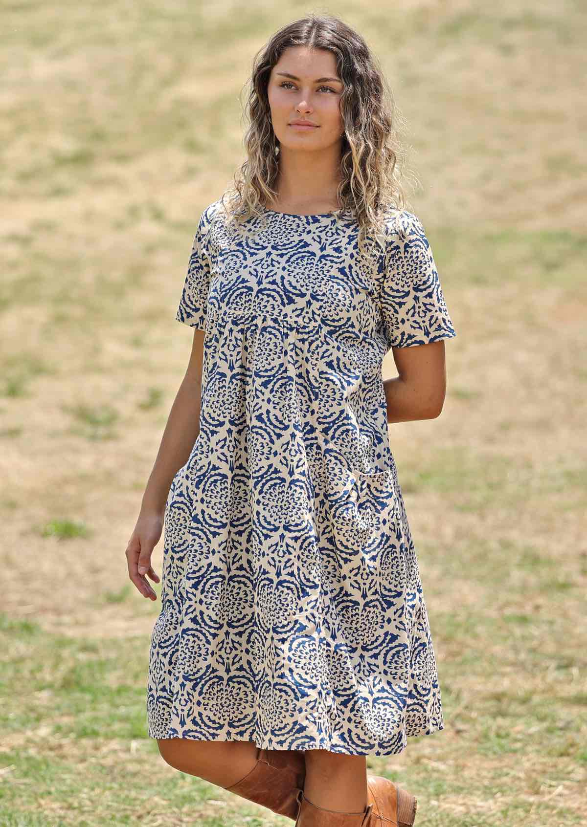 Model wears a dress featuring pockets and pin tucks.  