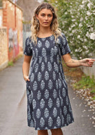 Woman in lane way with navy blue cotton Indian print summer dress with hand in pocket