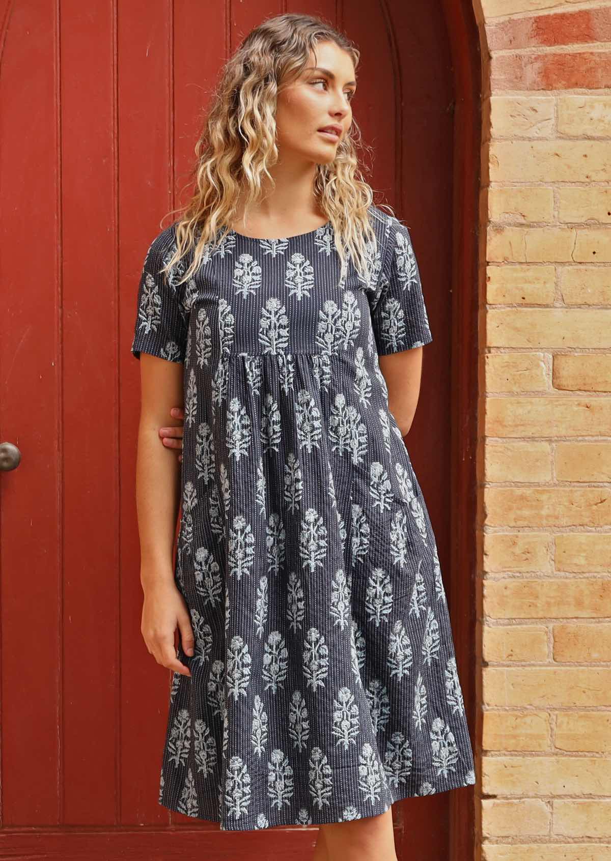 Woman standing in front of church door with navy blue cotton Indian print summer dress 