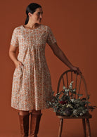 Model wears a 100% cotton floral dress with an empire waistline