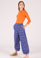 Model wears cotton wide leg pants with pockets and tapered ankles with small pleats