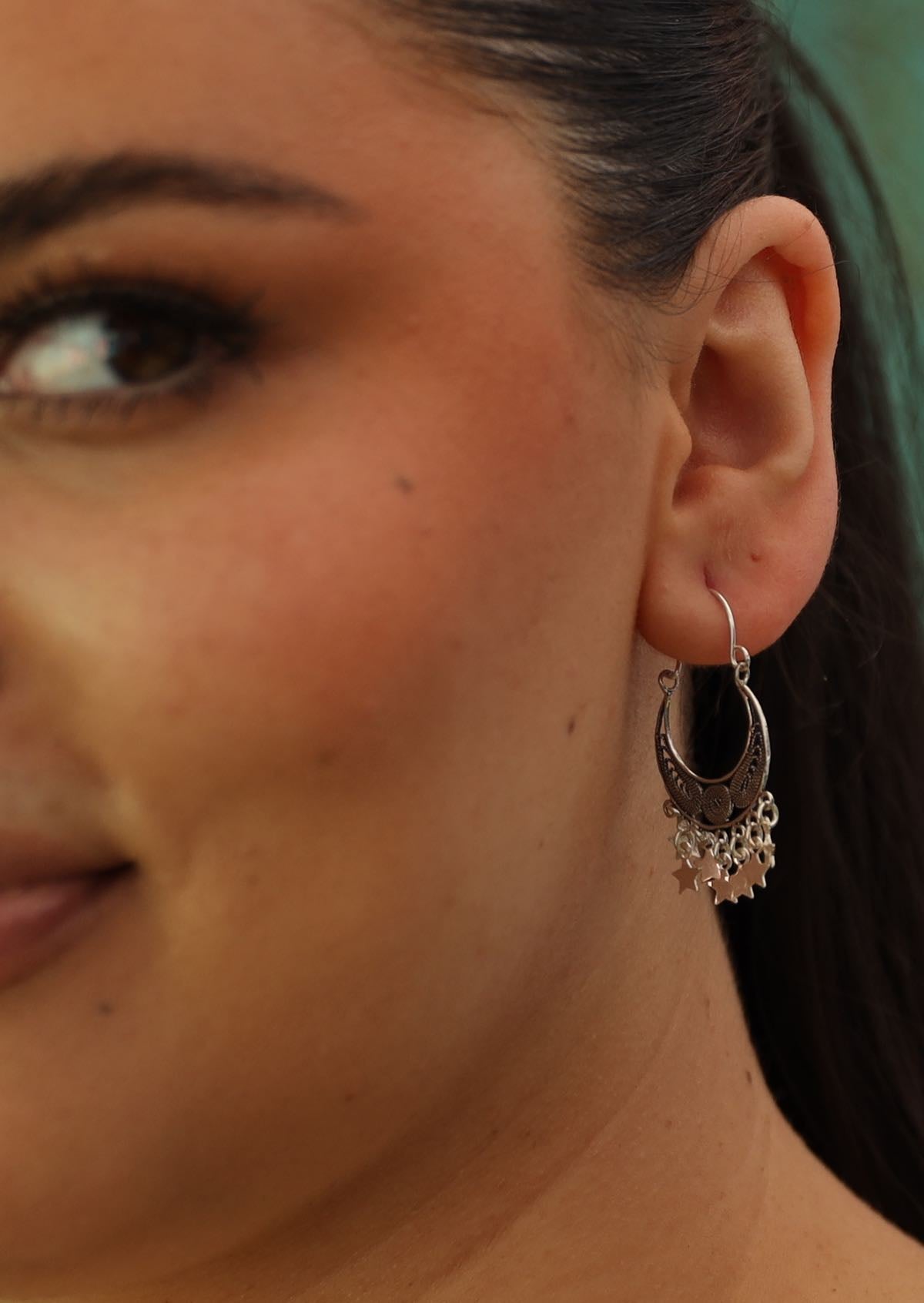 silver boho earrings with dangly stars and filigree work on woman's ear