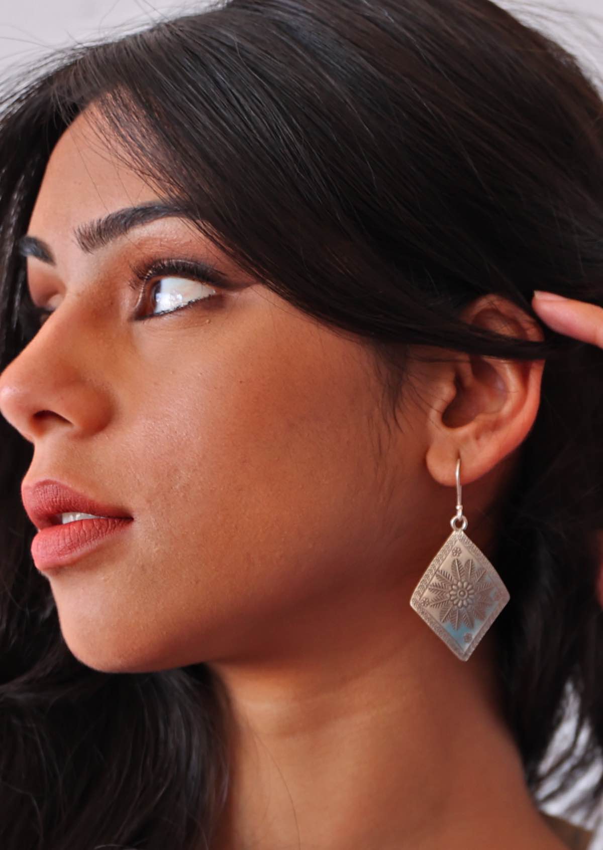 Close-up of a woman wearing a Large Hill Tribe silver earring with a textured design.