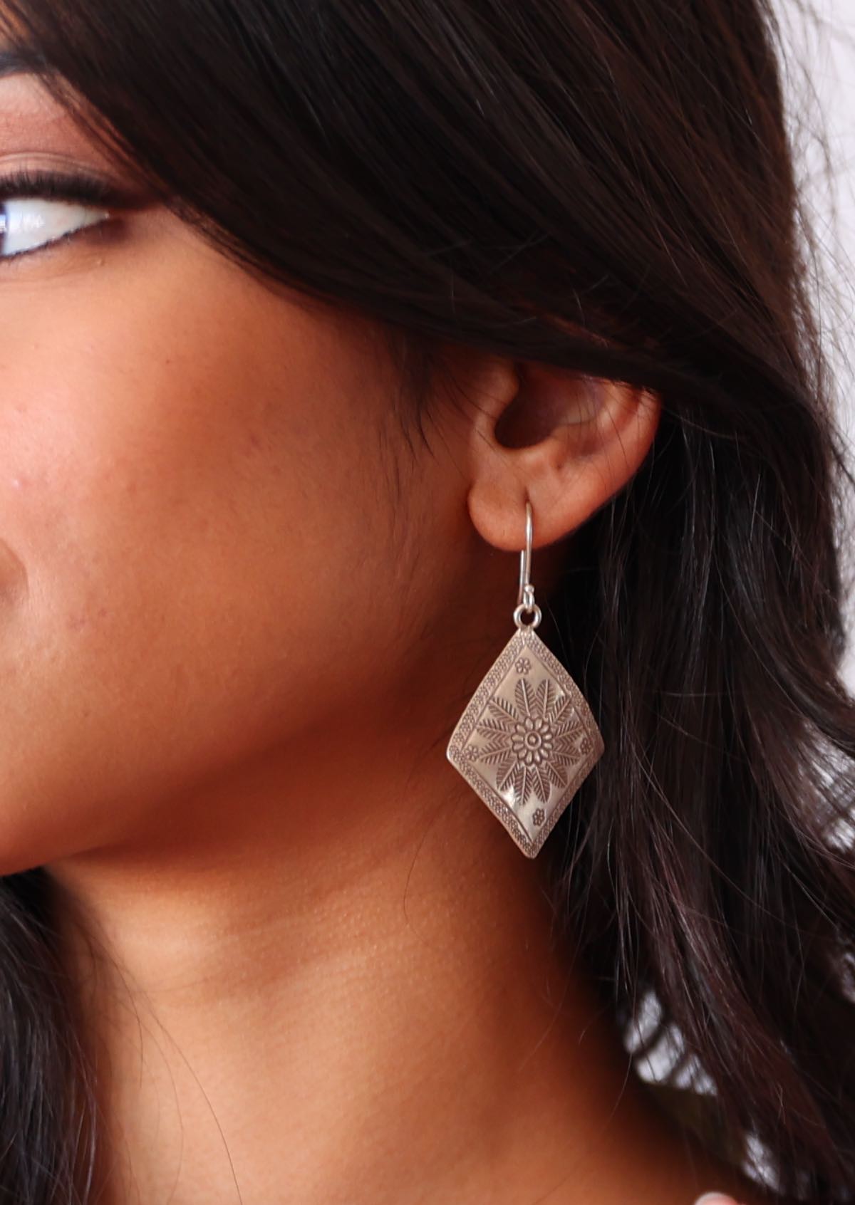 Close-up of a woman wearing a Large Hill Tribe silver earring with a textured design.