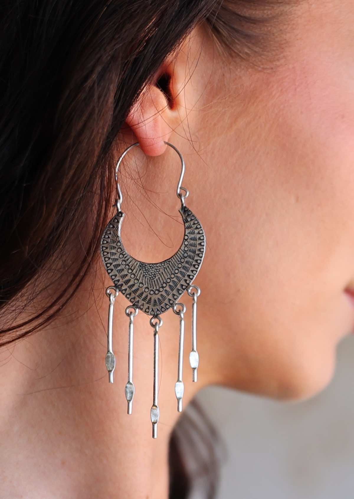 Close-up of a person wearing a Hill Tribe Silver hoop earring with dangling elements.