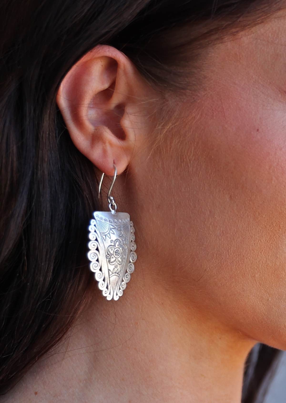 Close-up of a person wearing a Hill Tribe Silver Shield earring with intricate design.