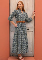 Model wears 100% cotton dress styled with a belt at the waist and sandals. 