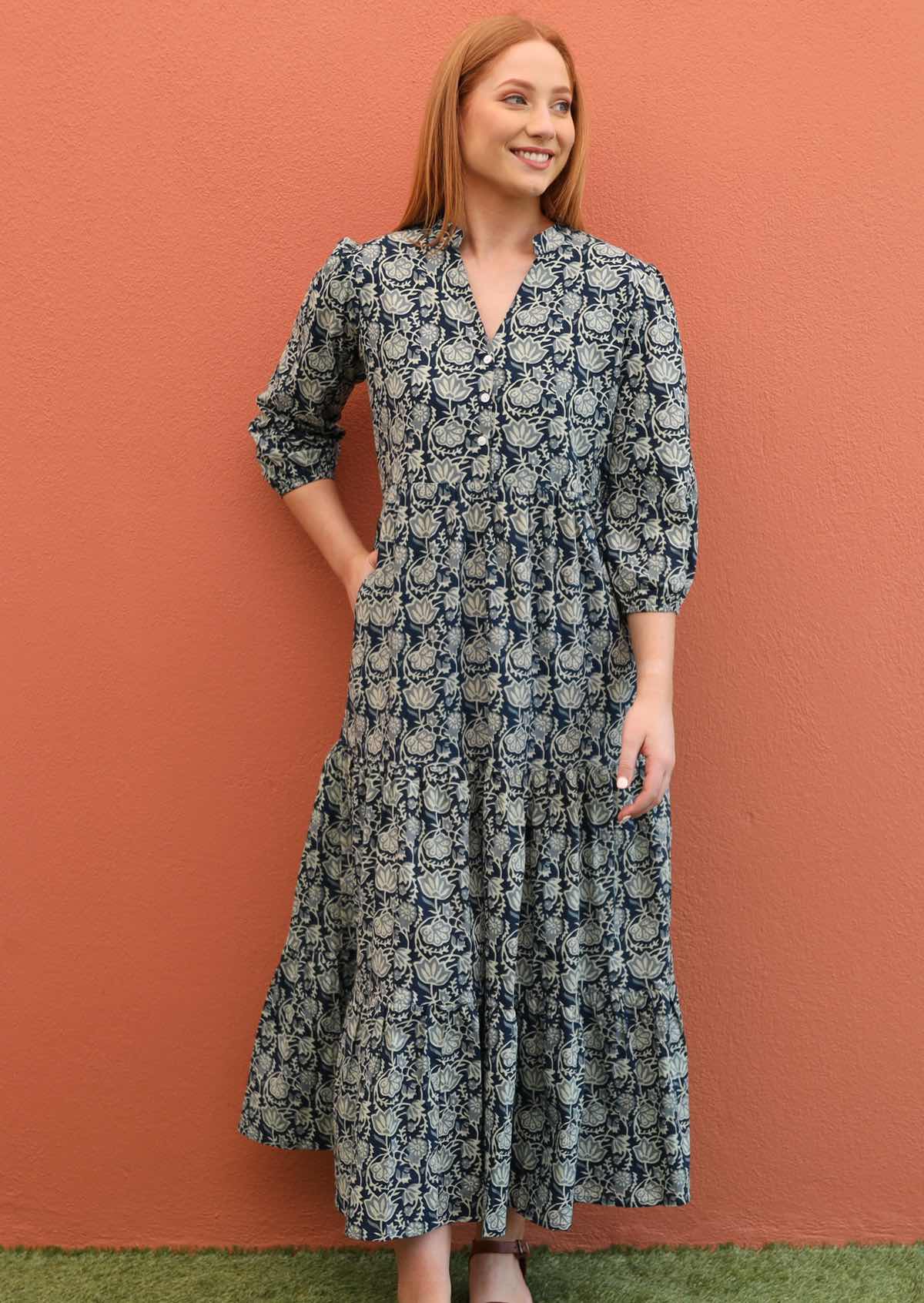 Women wears a maxi dress that features pockets, a v-neck and buttons down the front. 