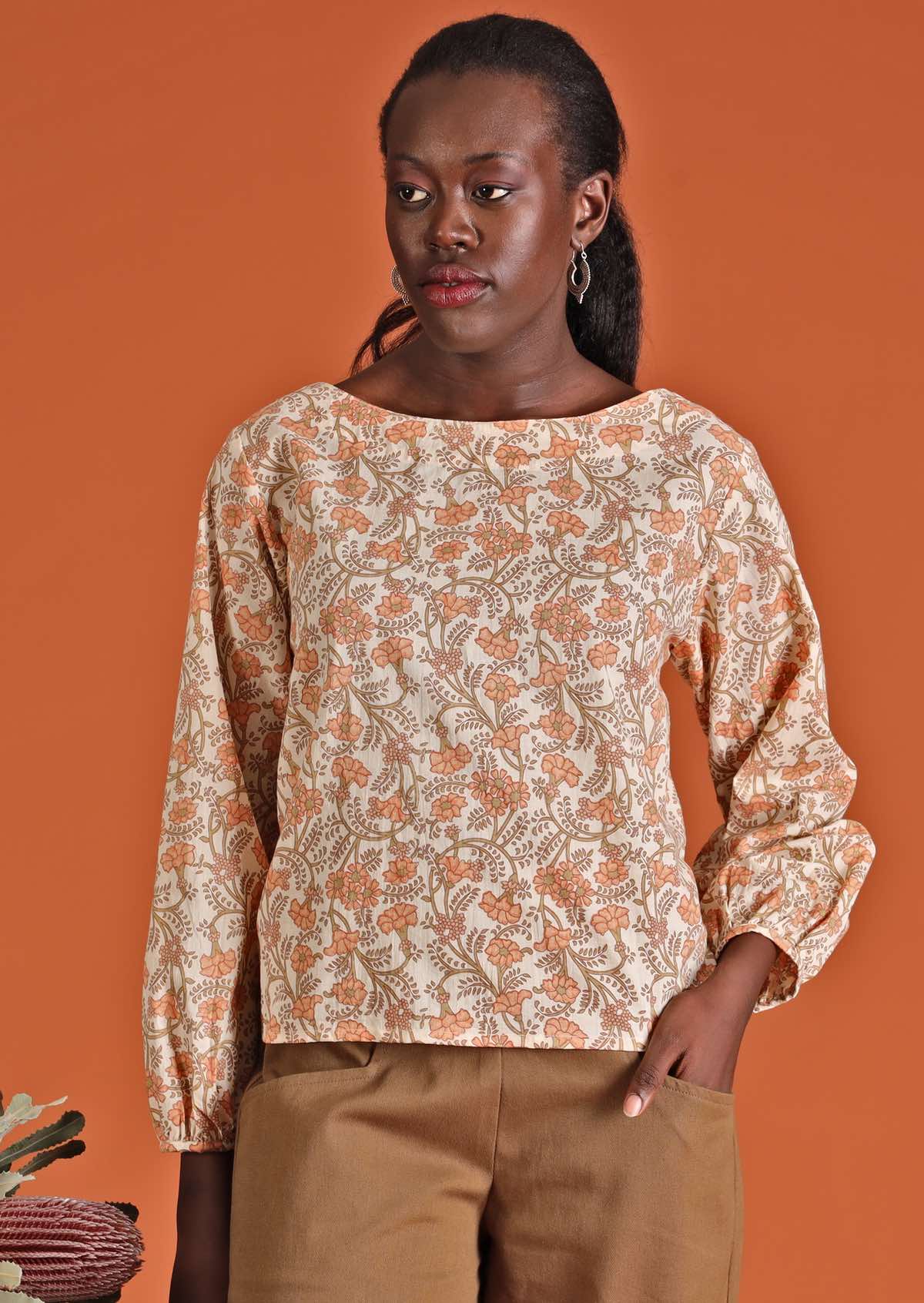 Model in cotton floral women's top, cream with apricot coloured flowers worn over cotton pants