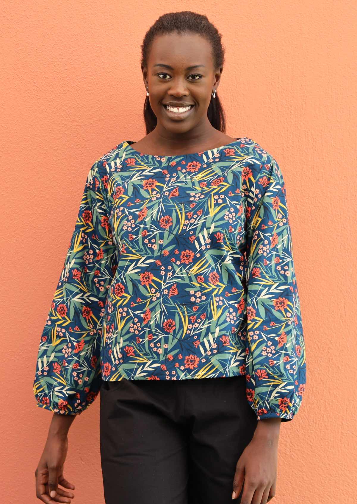 Smiling model wears a cotton top with bishop sleeves.