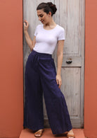 Smiling woman styles flowing pants with a plain top and sandals. 